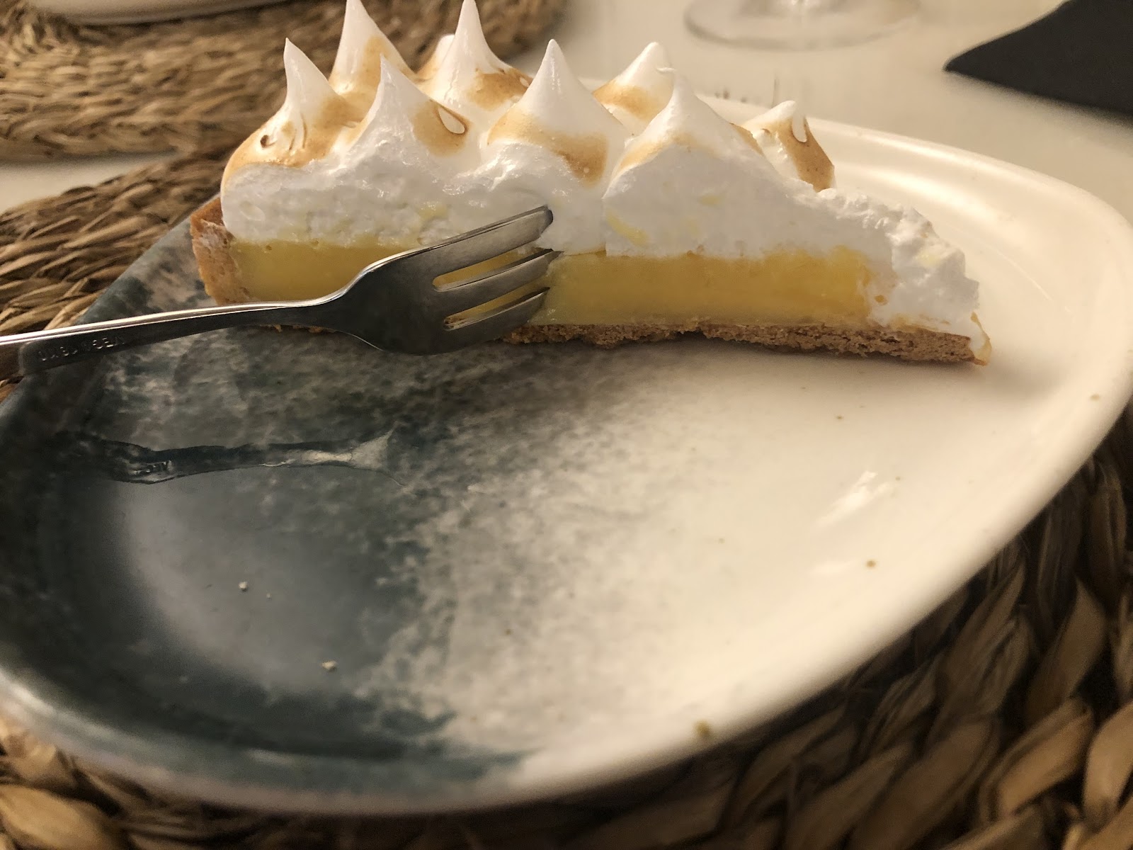 Porción de tarta de limón y merengue con picos tostados en plato blanco